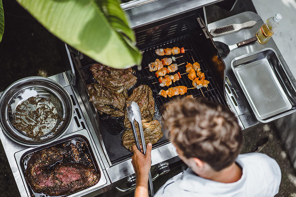 man tattoos makes barbecue grill meat outdoors