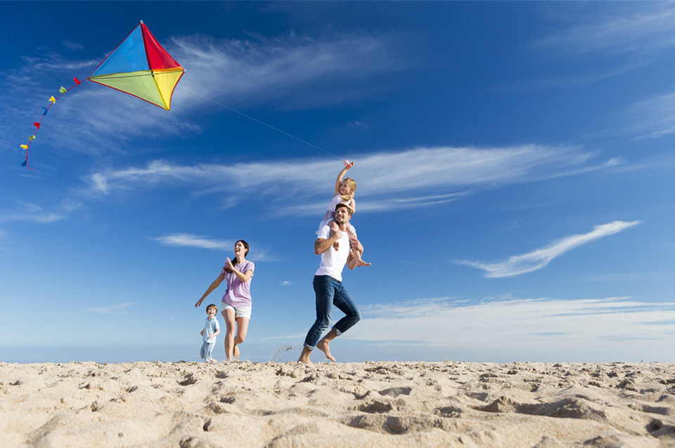 family flying kite on beach